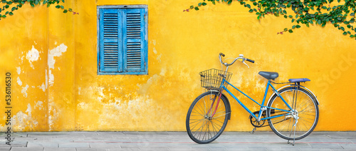 Old bicycle parking against yellow wall in Vietnam photo