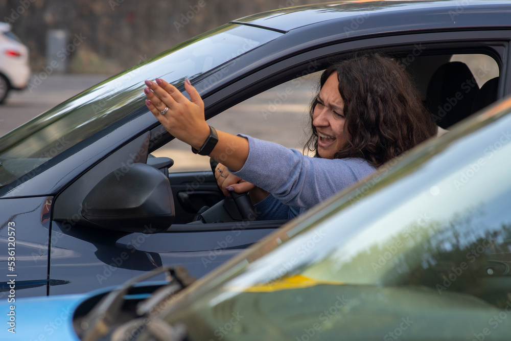 Naklejka premium Angry caucasian woman screaming and pointing with hand from side window while driving car.