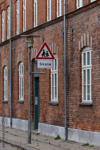 Fototapeta Naklejka Na Ścianę i Meble -  Koge, Denmark  A small street, an old brick building and a street sign for a school.