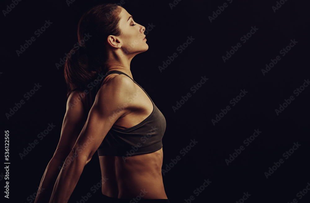 Strong sporty woman doing the arms and shoulders stretching exercise holding the hands in fist behind the back to relaxing in sport wear. Sports exercising. Closeup. Concept