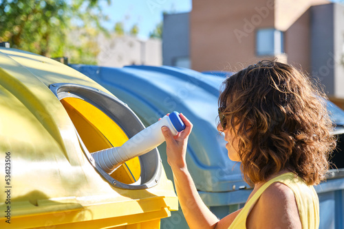 Obraz na plátně young woman throwing a container into the yellow recycling bin