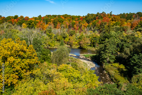 Beautiful View of the Credit River Valley From Above with Colorful Fall Foliage Against the blue Sky © chiyacat