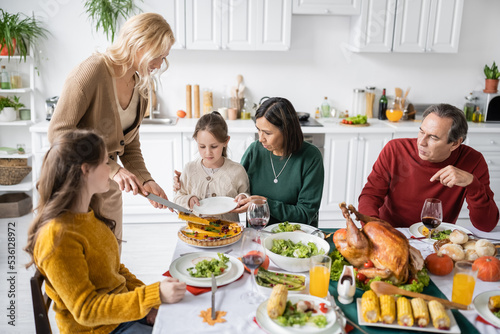 Multiethnic family celebrating thanksgiving with pie and turkey at home