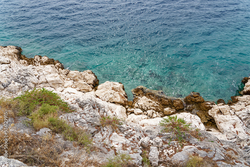 Steep coast, rocky cliff on Croatian Mediterranean coast photographed from above. The water is wonderfully clear and beautiful blue.