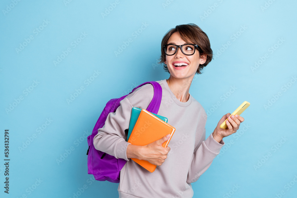Photo of satisfied stylish lady hold bag telephone planner wear glasses interested look empty space isolated on blue color background Photo of satisfied stylish lady hold bag telephone planner wear glasses interested look empty space isolated on blue color background