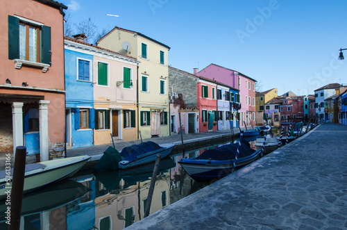 Barche ormeggiate in un canale di Burano con le tipiche case colorate in una giornata di sole 