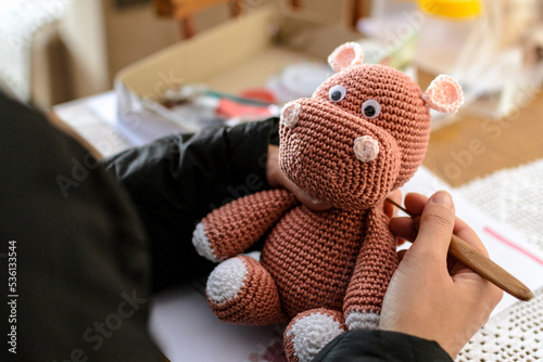 Mãos de uma artesã criando um hipopótamo de pelúcia usando a técnica de crochê amigurumi photo