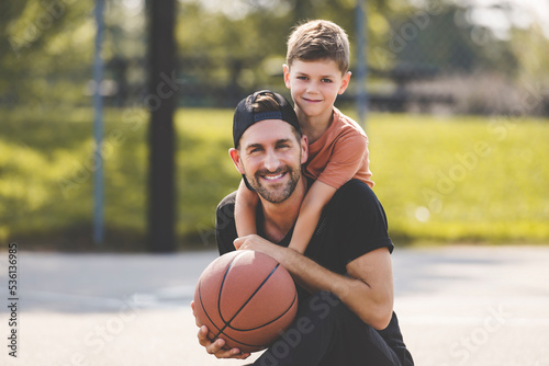 man and young boy playing basketball on a court, teaching little player and spending time outdoors