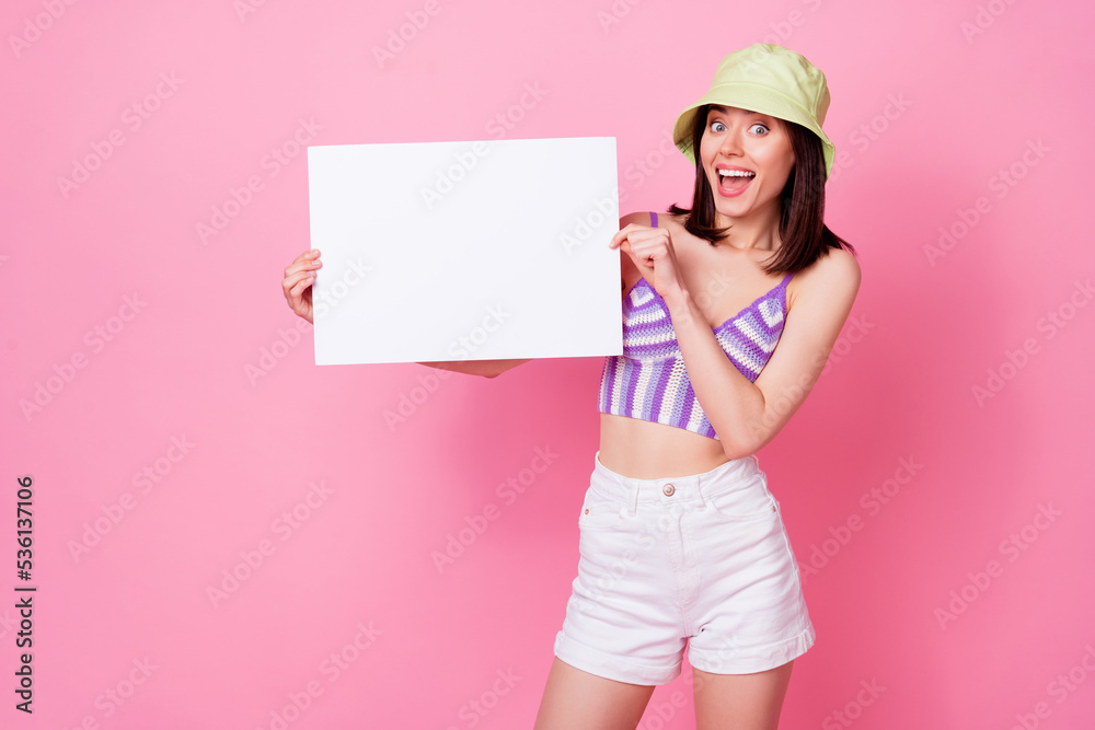 Photo portrait of charming young lady hold white copyspace impressed offer wear stylish tank top headwear isolated on pink color background Photo portrait of charming young lady hold white copyspace impressed offer wear stylish tank top headwear isolated on pink color background