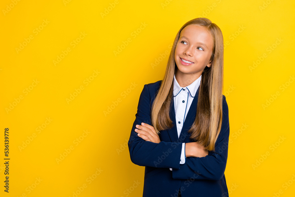 Portrait of positive schoolgirl with long hairstyle dressed blue jacket look empty space arms crossed isolated on yellow color background Portrait of positive schoolgirl with long hairstyle dressed blue jacket look empty space arms crossed isolated on yellow color background