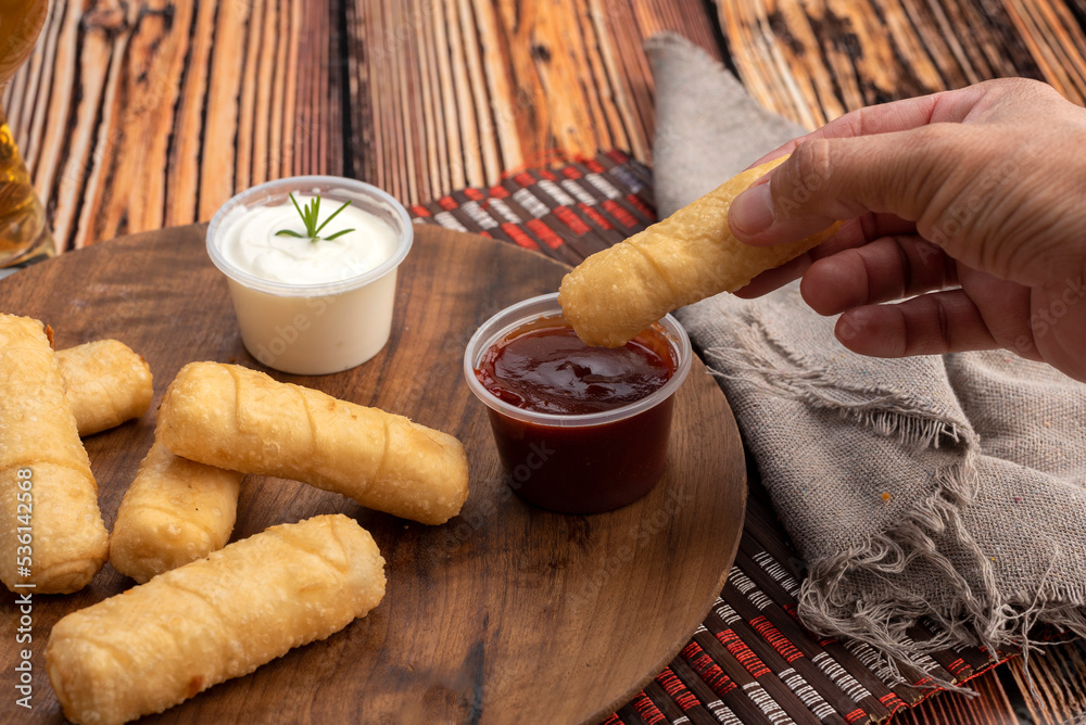 typical Venezuelan fried cheese tequeños on a round wooden plate with
