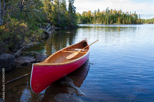 Red wood canoe on the shore of a Boundary Waters lake in morning light during autumn