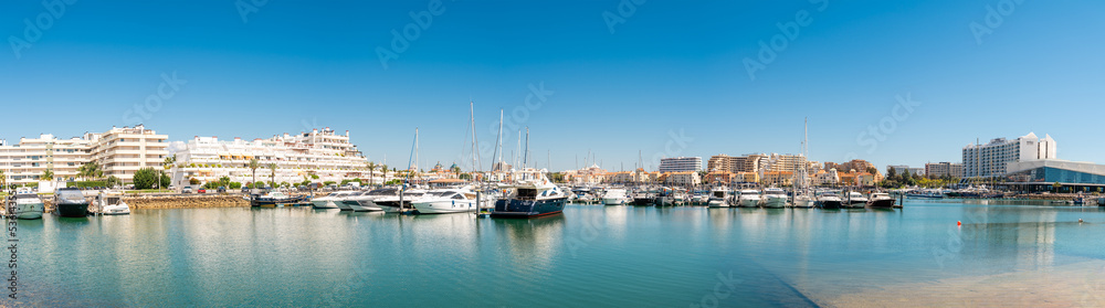 Panorama of luxury port of Vilamoura. Algarve region. Luxury travel destination in South of Portugal. Yacht docked, restaurants, luxury hotels and urbanisations