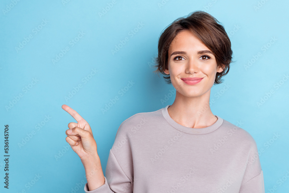 Photo of pretty girlish woman short hairstyle wear gray sweatshirt indicating empty space offer poster isolated on blue color background Photo of pretty girlish woman short hairstyle wear gray sweatshirt indicating empty space offer poster isolated on blue color background