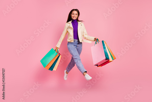 Full size photo of sweet young lady run shopping wear jacket jeans shoes isolated on pink color background © deagreez