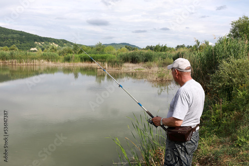 Senior man fishing in pond in summer