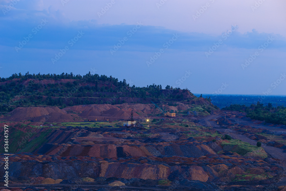 Waste rock dumps in mining operations. Waste dumping at the initial stage of metallurgy. Evening industrial landscape.