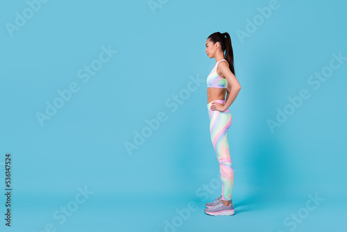 Full length profile photo of pretty korean lady stand look empty space wear trendy sporty clothes isolated on vibrant blue color background