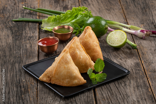 Sweet, tasty, fried indian dish samosha.Indian Delicious Deep Fried Breakfast Samosa Also Know as Samoosa isolated on Wooden texture Background photo