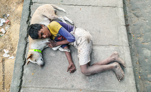 Homeless kid sleeping with his dog on the street. Concept of poverty, social differences, cruelty. Human best friend.