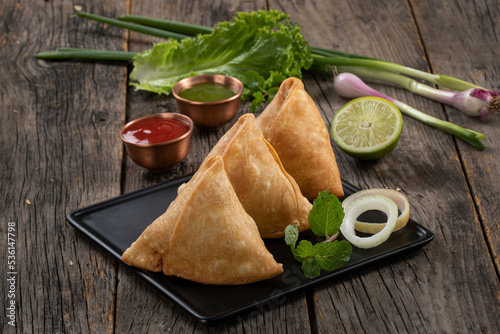 Sweet, tasty, fried indian dish samosha.Indian Delicious Deep Fried Breakfast Samosa Also Know as Samoosa isolated on Wooden texture Background photo