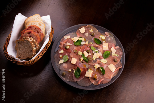 romantic dinner with carpaccio catfish deli meat basket of artisan breads caper mustard dijon top view photo