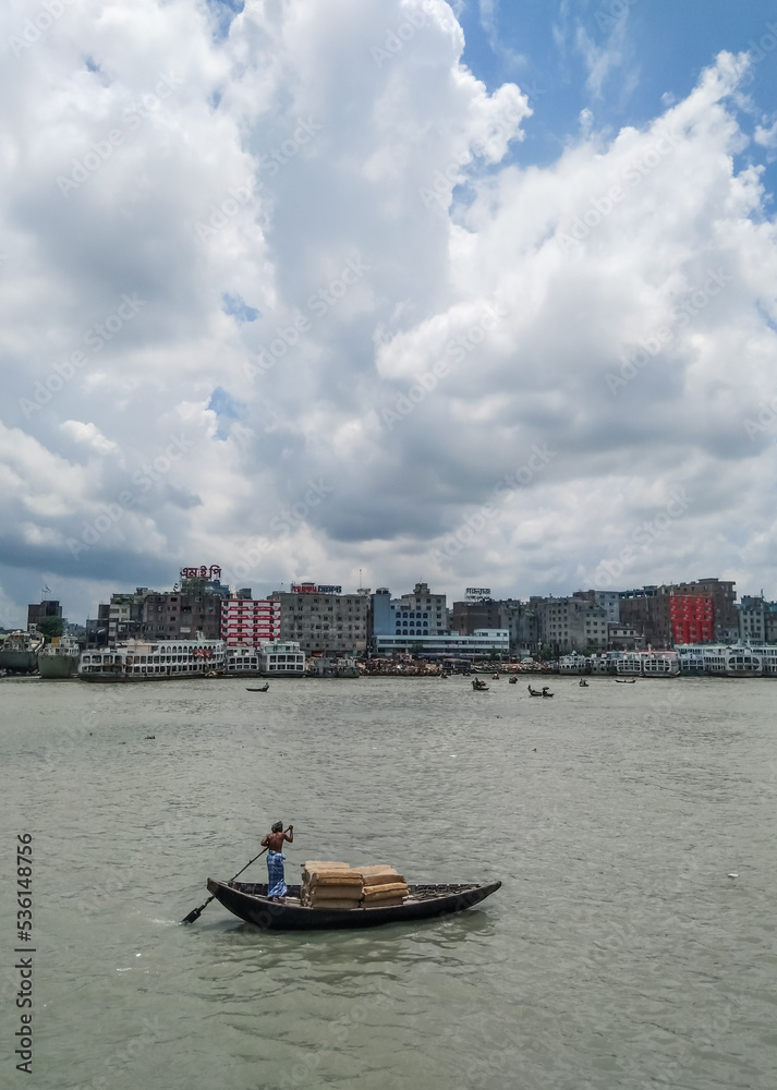 Obraz premium Beautiful landscape of Sadarghat river port on Buriganga river in Dhaka. Ferry boats on the river with a cloudy sky background.
