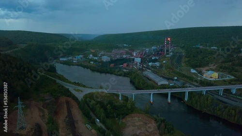 Flying above the river through small town and mountain landscape. Clip. Bridge across the wide river leading to the town. photo