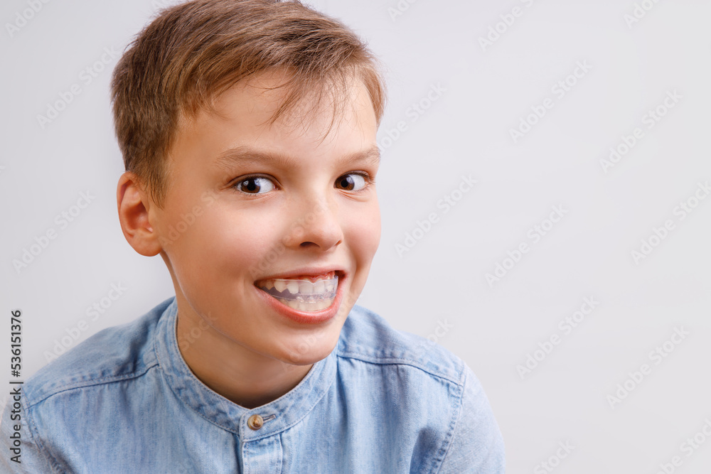 Boy is wearing orthodontic silicone trainer or night-guard case. Invisible braces helps of orthodontics problem. Close-up portrait. Mobile appliance for dental teeth correction. Boy is wearing orthodontic silicone trainer or night-guard case. Invisible braces helps of orthodontics problem. Close-up portrait. Mobile appliance for dental teeth correction.