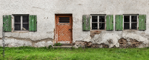 Panoramic photo of an old building exterior. Dirty door and windows on damaged wall. Travel, architecture concept