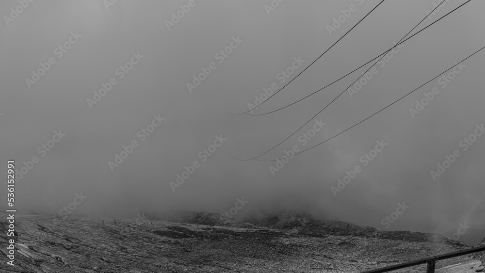 Fototapeta premium Cable car cables coming out of the clouds in Austrian Alps glacier