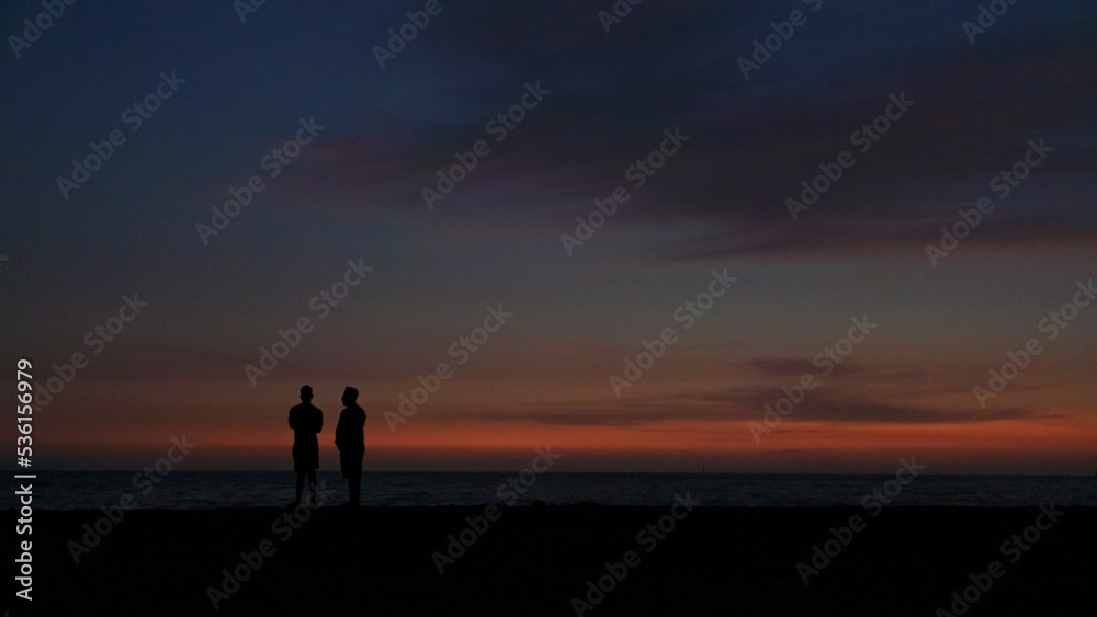 silhouette of a person walking on the beach at sunset silhouette of a person walking on the beach at sunset