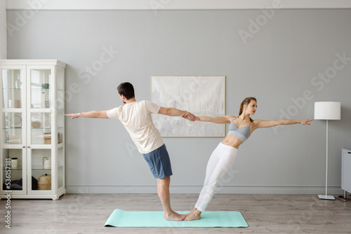 Young couple practicing acro yoga on mat in the house together. Home sports. High quality photo