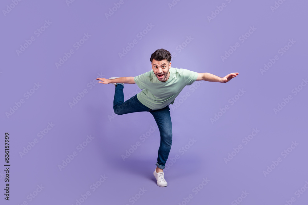 Full length photo of impressed overjoyed man stand on foot leg imagine can fly dream travel abroad isolated on purple color background