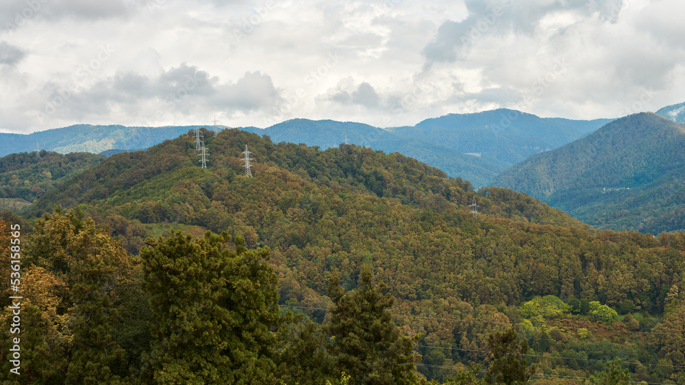 Mountain relief with metal poles of the power line passing through the top of the mountain.