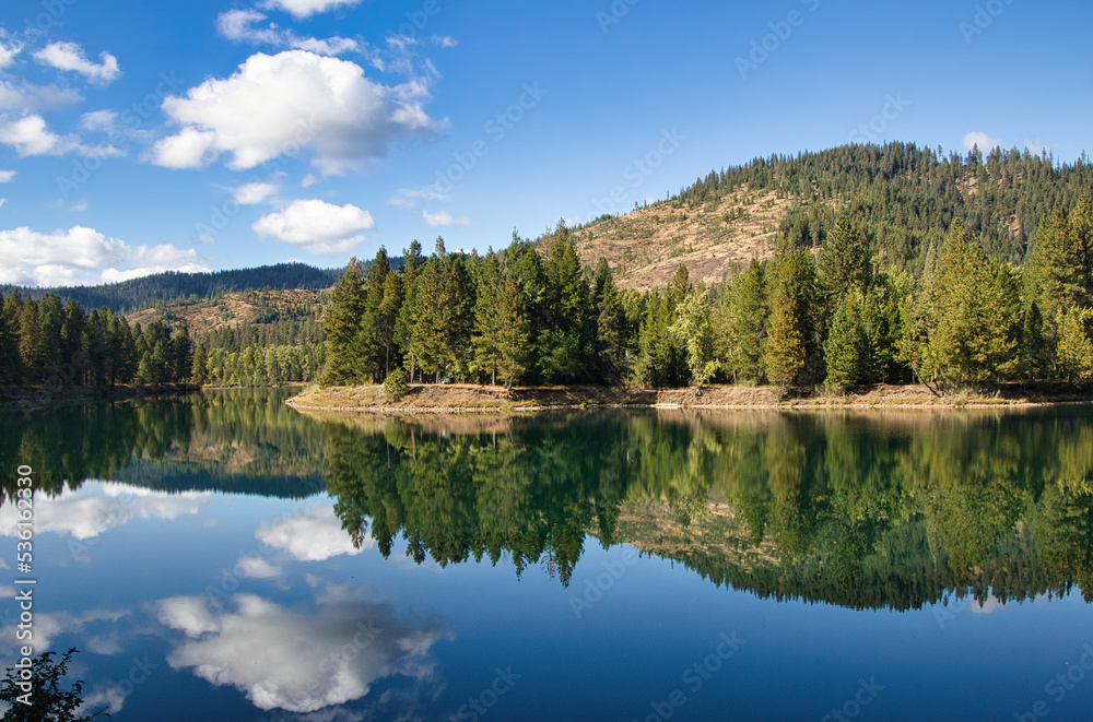 On a sunny Autumn day in Northwest Idaho, the sky and mountainous landscape is reflected in the glassy surface of a peaceful river. On a sunny Autumn day in Northwest Idaho, the sky and mountainous landscape is reflected in the glassy surface of a peaceful river.