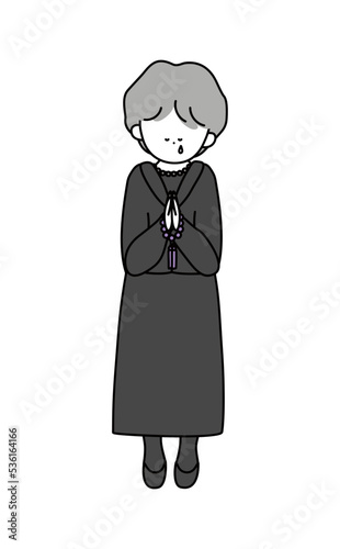 数珠を持って拝む泣いている喪服の年配女性白