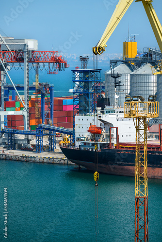 industrial seaport infrastructure, sea, cranes and dry cargo ship, grain silo and bulk carrier vessel, concept of sea cargo transportation