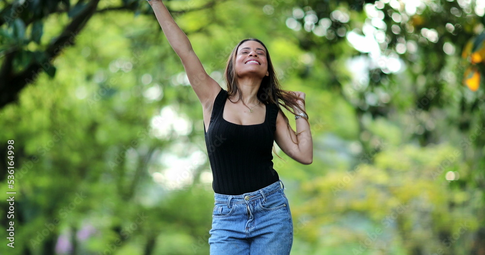 Hispanic woman celebrating good news message on cellphone device outside Hispanic woman celebrating good news message on cellphone device outside
