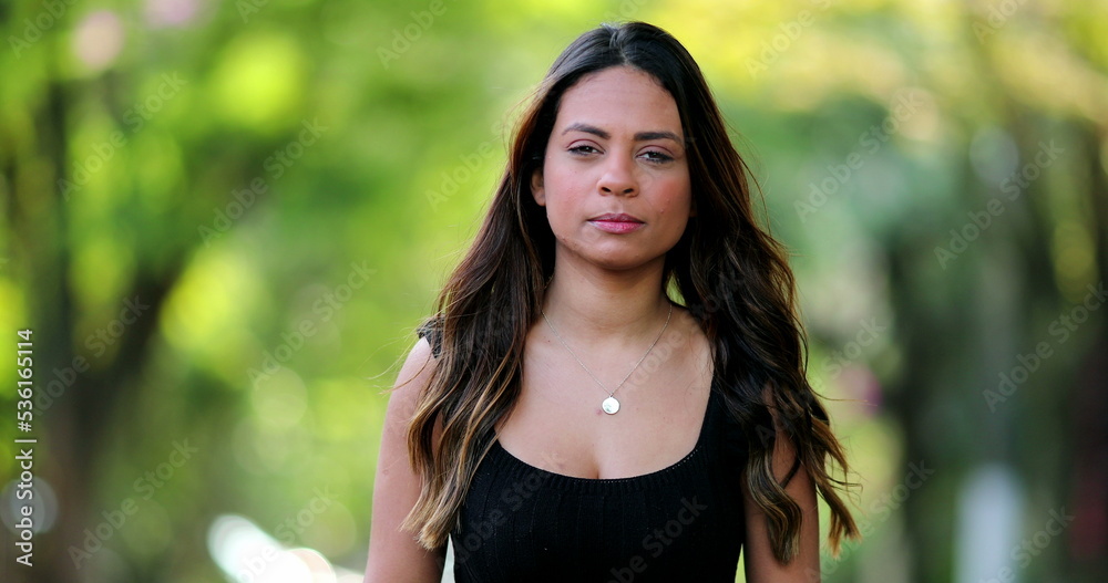 Hispanic latina young woman standing outside looking at camera Hispanic latina young woman standing outside looking at camera