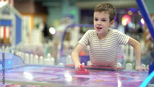 A boy of seven years old enjoys playing air hockey in the playground for entertainment photo