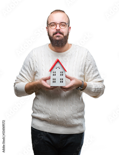 Young caucasian real state agent man holding house isolated background with a confident expression on smart face thinking serious