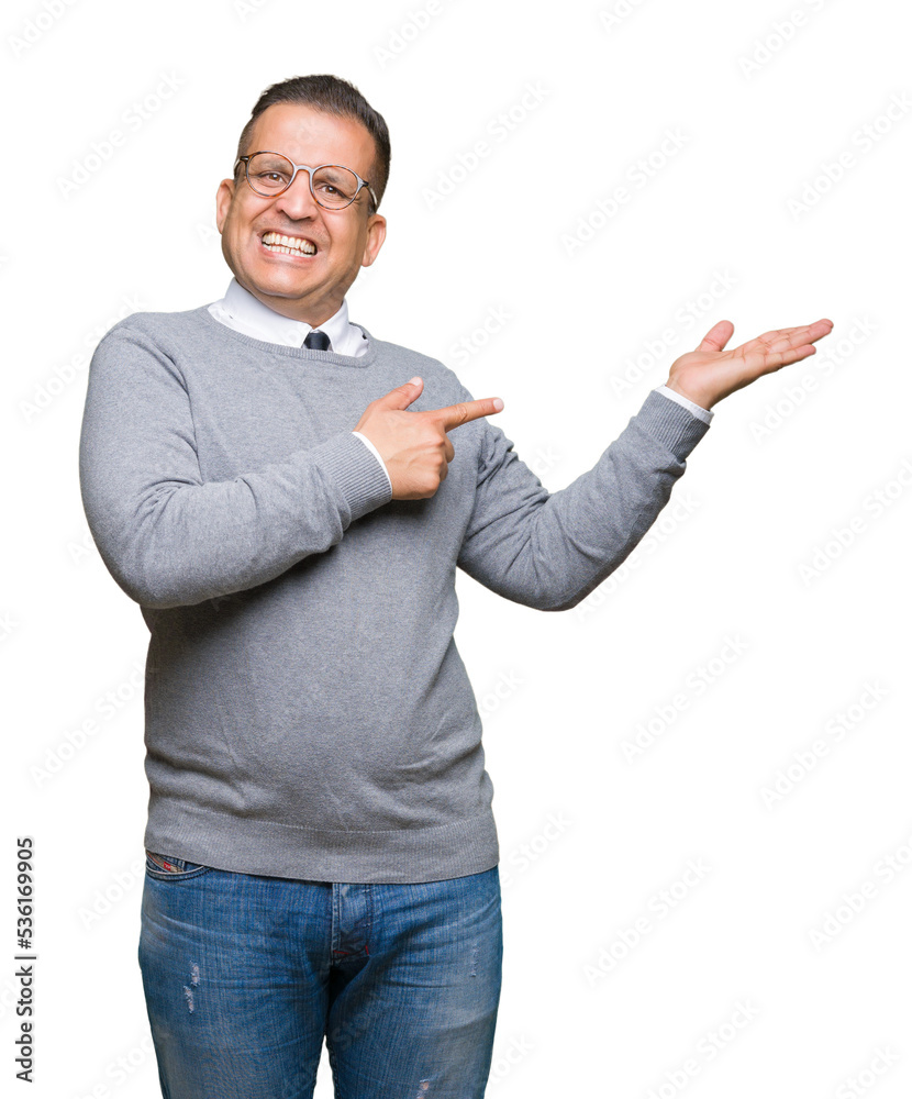Middle age bussines arab man wearing glasses over isolated background amazed and smiling to the camera while presenting with hand and pointing with finger. Middle age bussines arab man wearing glasses over isolated background amazed and smiling to the camera while presenting with hand and pointing with finger.