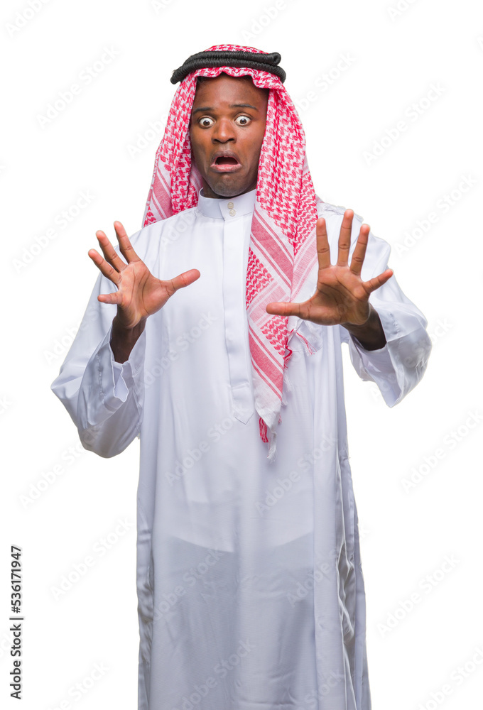 Young arabic african man wearing traditional keffiyeh over isolated background afraid and terrified with fear expression stop gesture with hands, shouting in shock. Panic concept.