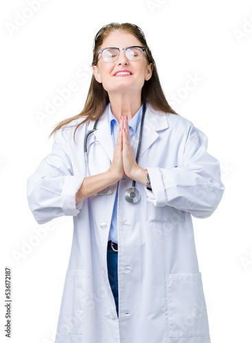 Middle age mature doctor woman wearing medical coat over isolated background begging and praying with hands together with hope expression on face very emotional and worried. Asking for forgiveness