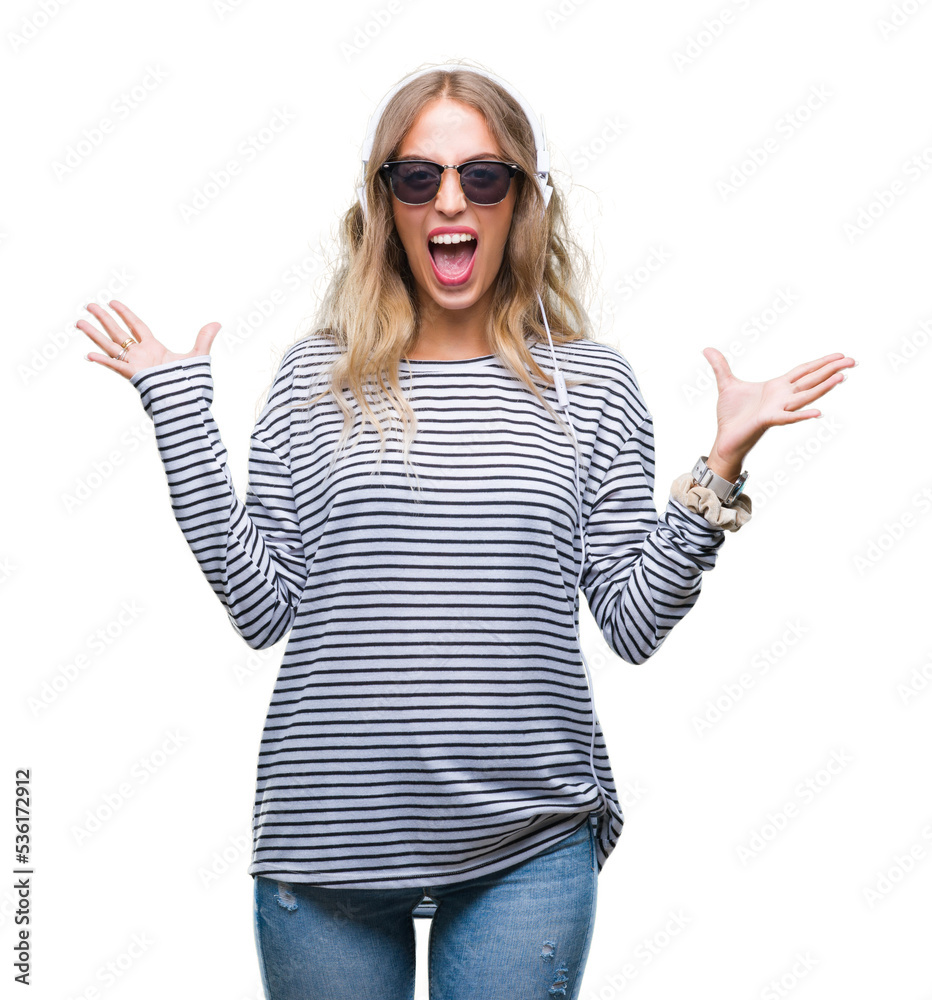 Beautiful young blonde woman wearing headphones and sunglasses over isolated background celebrating crazy and amazed for success with arms raised and open eyes screaming excited. Winner concept Beautiful young blonde woman wearing headphones and sunglasses over isolated background celebrating crazy and amazed for success with arms raised and open eyes screaming excited. Winner concept