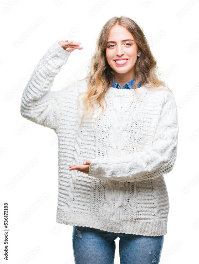 Beautiful young blonde woman wearing winter sweater over isolated background gesturing with hands showing big and large size sign, measure symbol. Smiling looking at the camera. Measuring concept. Beautiful young blonde woman wearing winter sweater over isolated background gesturing with hands showing big and large size sign, measure symbol. Smiling looking at the camera. Measuring concept.
