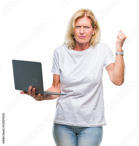 Middle age blonde woman using computer laptop over isolated background annoyed and frustrated shouting with anger, crazy and yelling with raised hand, anger concept