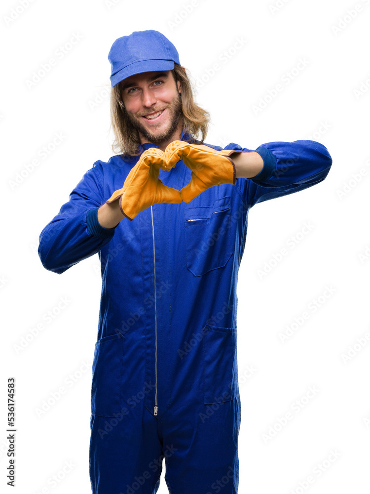 Young handsome mechanic man with long hair over isolated background smiling in love showing heart symbol and shape with hands. Romantic concept. Young handsome mechanic man with long hair over isolated background smiling in love showing heart symbol and shape with hands. Romantic concept.