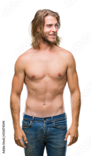 Young handsome shirtless man with long hair showing sexy body over isolated background looking away to side with smile on face, natural expression. Laughing confident.